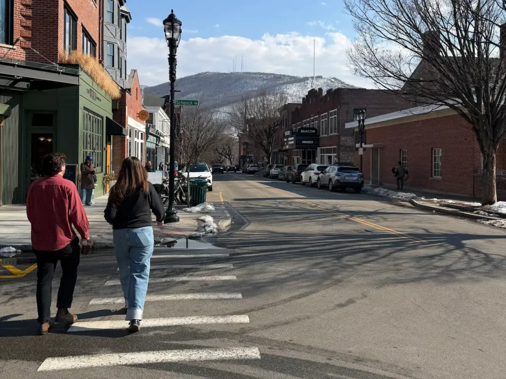 two people on a crosswalk left of a main street road