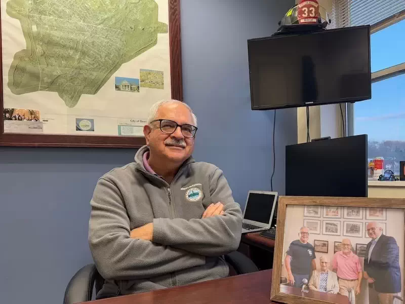  Mayor Lee Kyriacou in his office at Municipal Plaza with a commemorative photograph of Beacon’s most recent mayors, including Clara Lou Gould. 