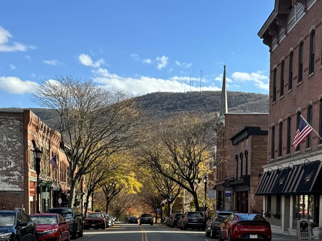 Beacon's Main Street with Mount Beacon in the background and red brick buildings housing shops either side of the street.