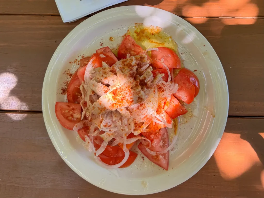 plate of ripe sliced tomatoes with tuna and onions on top