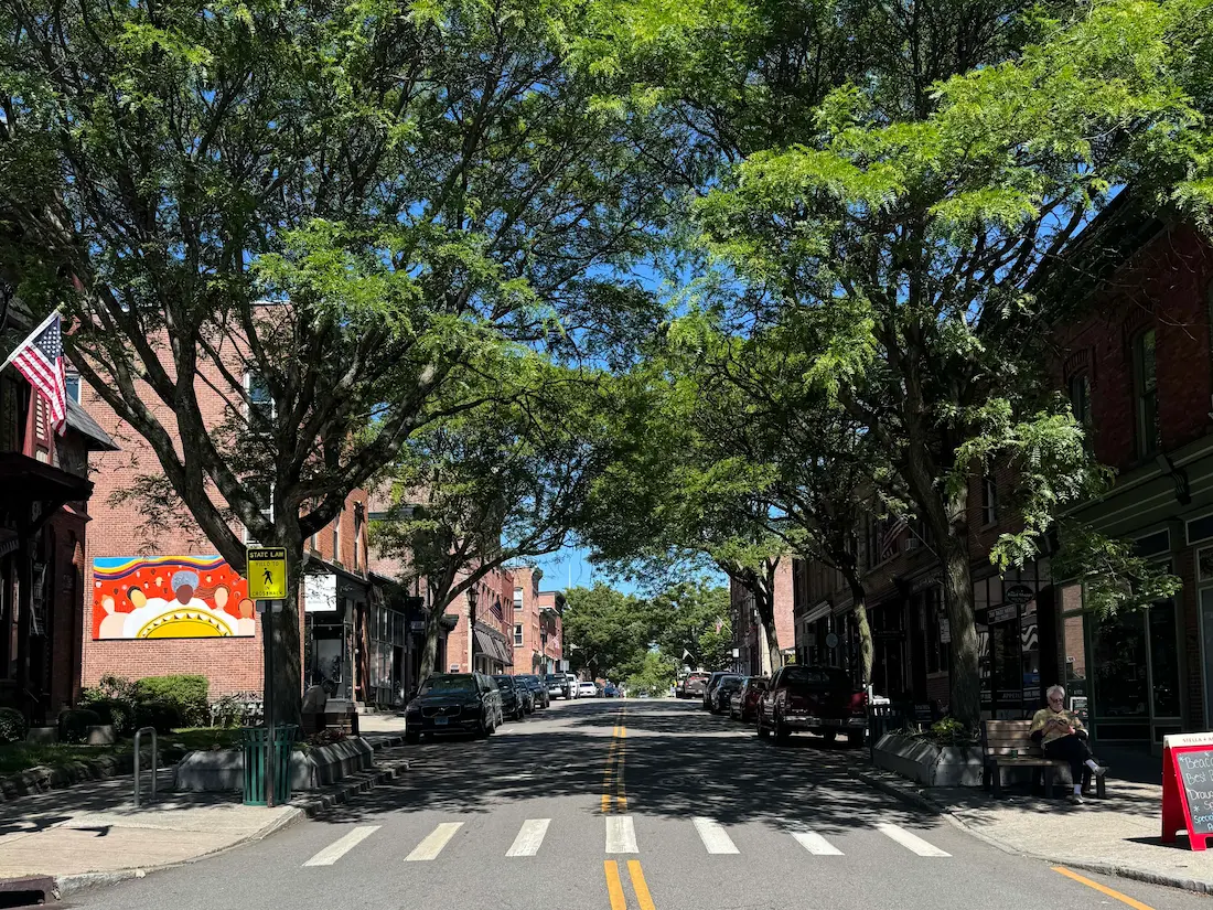 Beacon's Main Street with tree lined sidewalks, red brick buildings and a crosswalk connecting the two sidewalks.