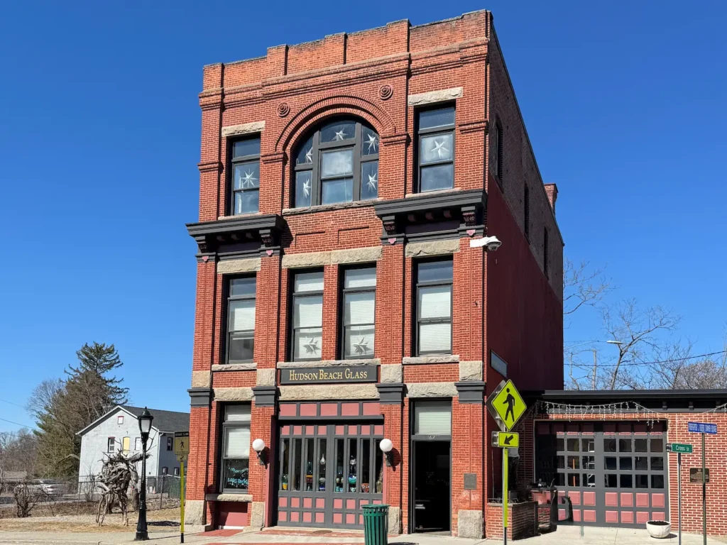 A victorian three story red brick building with many windows, with a bright blue sky in the background