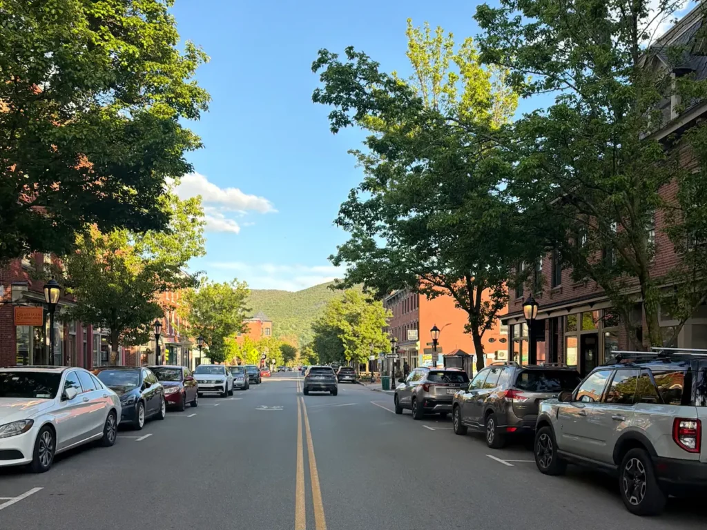 Beacon, NY's Main Street in spring, with leafy tree-lined streets and Mount Beacon in the background.