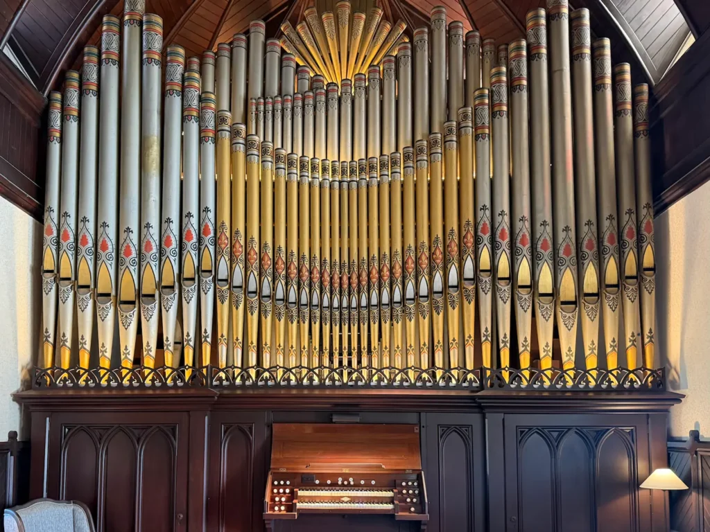 A Victorian 58 pipe organ ornately restored with gold and etchings set in a dark wooden casing.